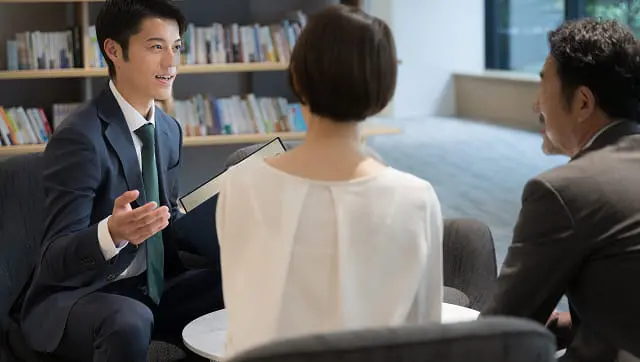 本棚のある空間で顧客に説明を行うファイナンシャルプランナー